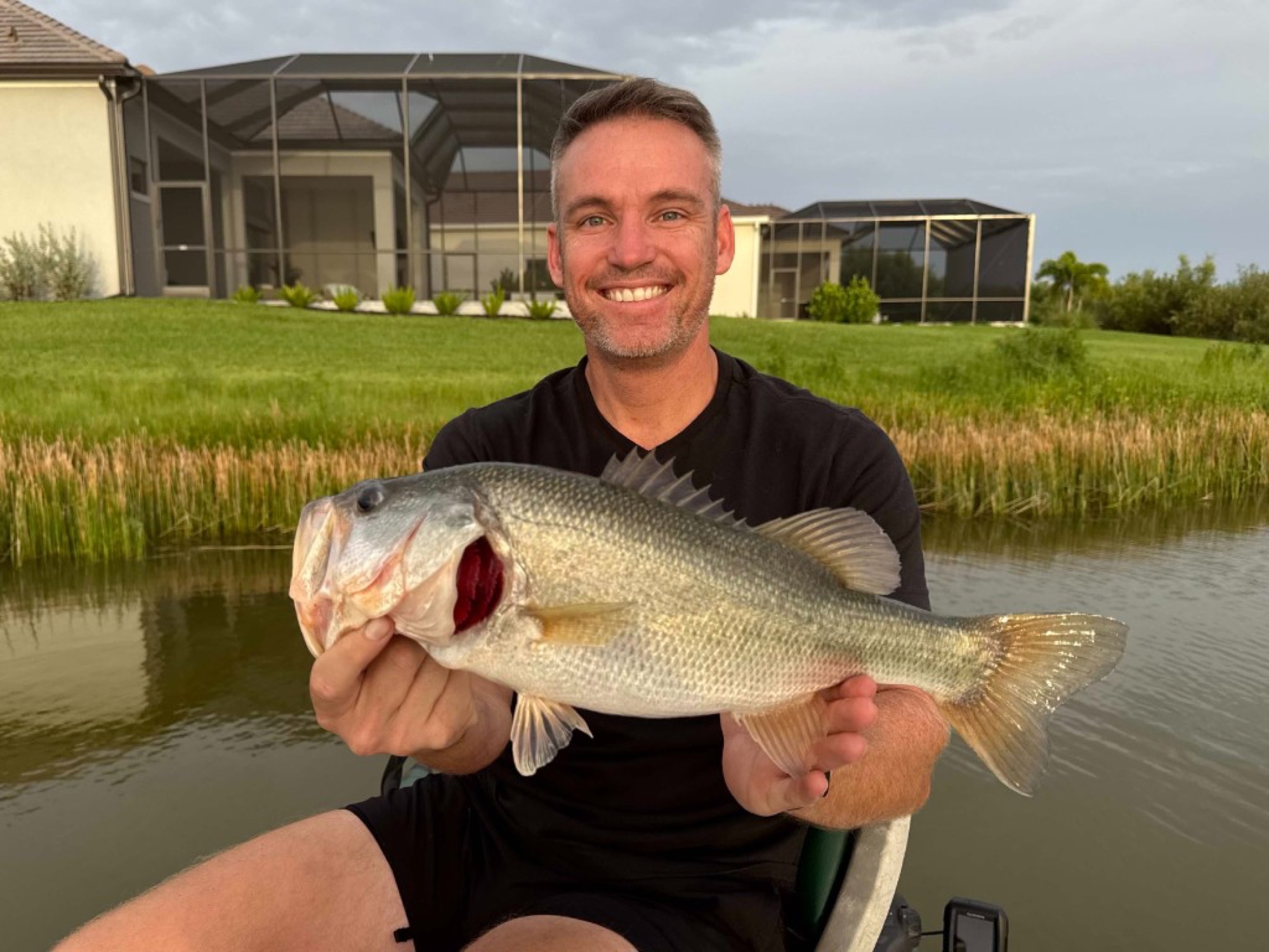 Jordan holding a largemouth bass on the water